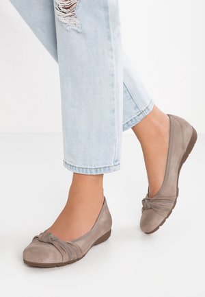 Lysbrune ruskinds ballerinaer med en knyttet detalje ved tæerne, prydet med dekorativ syning og en lav, polstret hæl, parret med opkravede denimbukser.