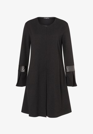 Robe noire avec un col rond et des manches longues. Présente un tissu texturé avec des accents en cuir noir brillant aux ouvertures des manches.
