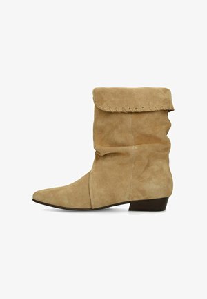 Beige suède laarzen tot halverwege de kuit met een slouchy uitstraling, een omgevouwen bovenkant en een lage gestapelde hak, zijaanzicht op een witte achtergrond.