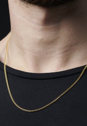 Gullkjede med tvunnet design, liggende på en svart crew-neck skjorte; glatt tekstur, blank overflate og ensartet farge.
