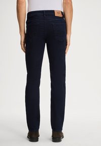 Jeans in denim blu navy con taglio dritto, etichetta sul retro e due tasche posteriori con dettagli di cucitura distintivi.