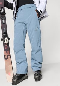 Világoskék sínadrág tartós, vízálló anyagból készült. Erősített térdek, logó részlet és kényelmes illeszkedés jellemzi, amely ideális téli sportokhoz.