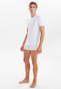 Hvid kortærmet t-shirt og matchende boxershorts lavet af et glat, strækbart stof, med en rund halsudskæring og en tætsiddende pasform.