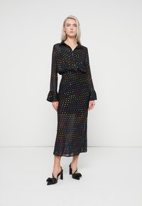 Μαύρο φόρεμα με πουά σχέδιο από διάφανο ύφασμα, διαθέτει γιακά, μακρυά μανίκια με φουσκωτές μανσέτες και μεσαίου μήκους, στενή γραμμή.