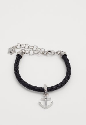 Bracelet en cuir tressé noir avec breloque ancre en argent et fermoir chaîne en argent avec un petit détail tête de lion.