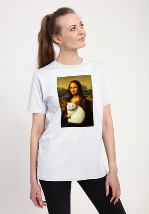 Vrouw met een paardenstaart draagt een wit T-shirt met de Mona Lisa die een witte kat vasthoudt. Ze kijkt licht omhoog en opzij.