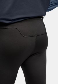 Black athletic leggings with a smooth texture, featuring stitched seams and a high waist design. The fabric is stretchy and form-fitting.