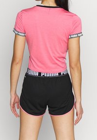 Rosa figurnära t-shirt med svart kant och logotyp på ärmarna, ihopparad med svarta shorts med rosa accent vid kanten och logotyp på midjan.