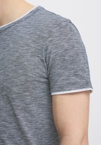 Tricou gri cu mânecă scurtă, cu un model heathered. Are un guler alb simplu și o croială lejeră. Material moale și ușor.