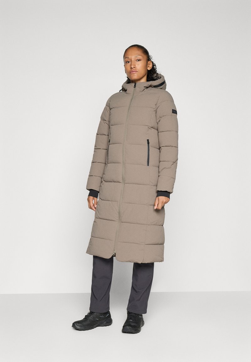 Lange, puffy jas in beige met een rits aan de voorkant, capuchon en twee zijzakken. Bevat horizontale stiksels en zwarte accenten op de ritsen.