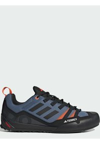 Buty trekkingowe z ciemnoniebieską i czarną tkaniną wierzchnią, czarną gumową podeszwą i pomarańczowymi akcentami. Posiadają teksturowane wykończenie oraz wzmocniony czubek.