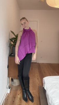 Lilla asymmetrisk topp med drapert stoff og halterneck, kombinert med svarte leggings og svarte spisse støvler som rekker til kneet.
