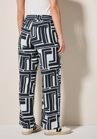 Stora byxor gjorda av lättviktig tyg, med ett djärvt svart och vitt geometriskt mönster. Elastisk midja med sidofickor.