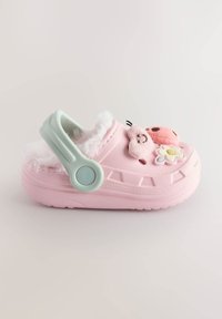 Lyserød trædepudel med pelsforing og mintgrøn rem, med dekorative detaljer inklusive en blomst og en legesyg figur, i letvægtsmateriale.