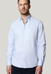Jasnoniebieska koszula zapinana na guziki z klasycznym ko łnierzykiem, długimi rękawami i gładką fakturą. Posiada białe guziki i dopasowany krój.