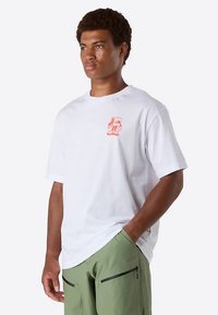Camiseta de algodón blanca con un pequeño diseño gráfico naranja en el lado izquierdo del pecho. Corte relajado, con mangas cortas y cuello redondeado.