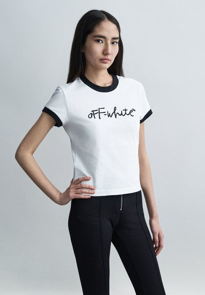 T-shirt blanc court avec bords côtelés noirs, arborant le logo "OFF-white" en cursive. Porté avec un pantalon noir ajusté, texture lisse.