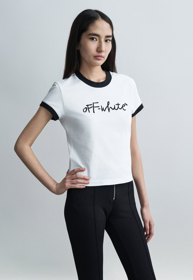 Λευκό κοντό t-shirt με μαύρα ριμπ περιγράμματα, με το λογότυπο "OFF-white" σε καλλιγραφικό στυλ. Φοριέται με εφαρμοστά μαύρα παντελόνια, με ομαλή υφή.