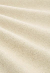 Jasnobeżowa tkanina o miękkiej, teksturowanej powierzchni, ukazująca delikatne fale oraz subtelne różnice w odcieniu. Idealna do różnych zastosowań tekstylnych.