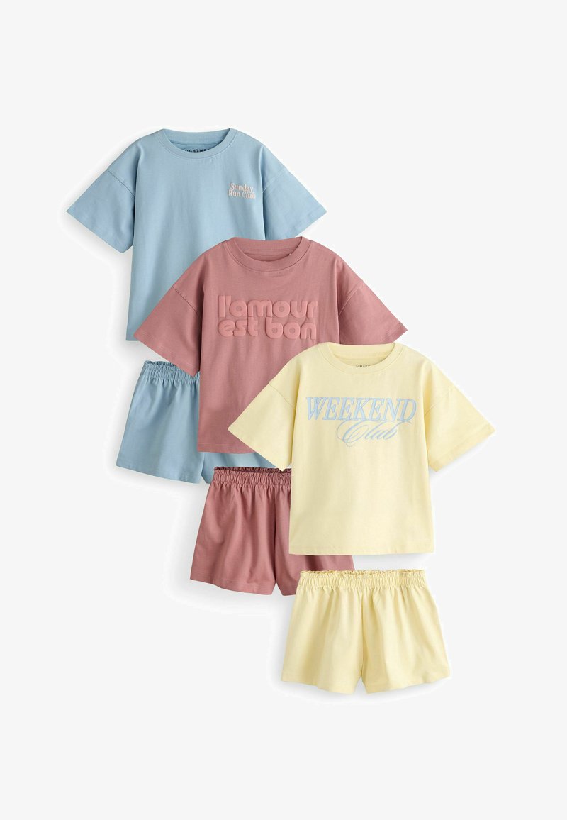 Tre sæt afslappede t-shirts med korte ærmer og shorts med elastisk talje i pastelblå, lyserød og gul med teksttryk på skjorterne.
