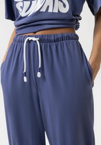 Mörkblå joggers med elastisk midja och vit dragsko. Mjuk tygkvalitet med sidofickor och avslappnad passform.
