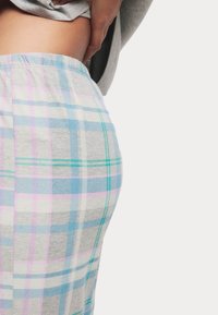 Grijze geruite loungebroeken hebben een patroon van blauwe, groene en roze checks. De stof ziet er zacht en comfortabel uit, met een elastische tailleband.
