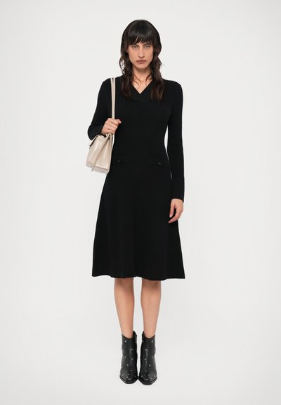 Mustda põlvepikkune must kudumkleit, pika varrukaga, sügava V-kaelusega ja kahe esikäe taskuga. Kombineeritud beeži kotti ja mustade studidega ankle botastega.