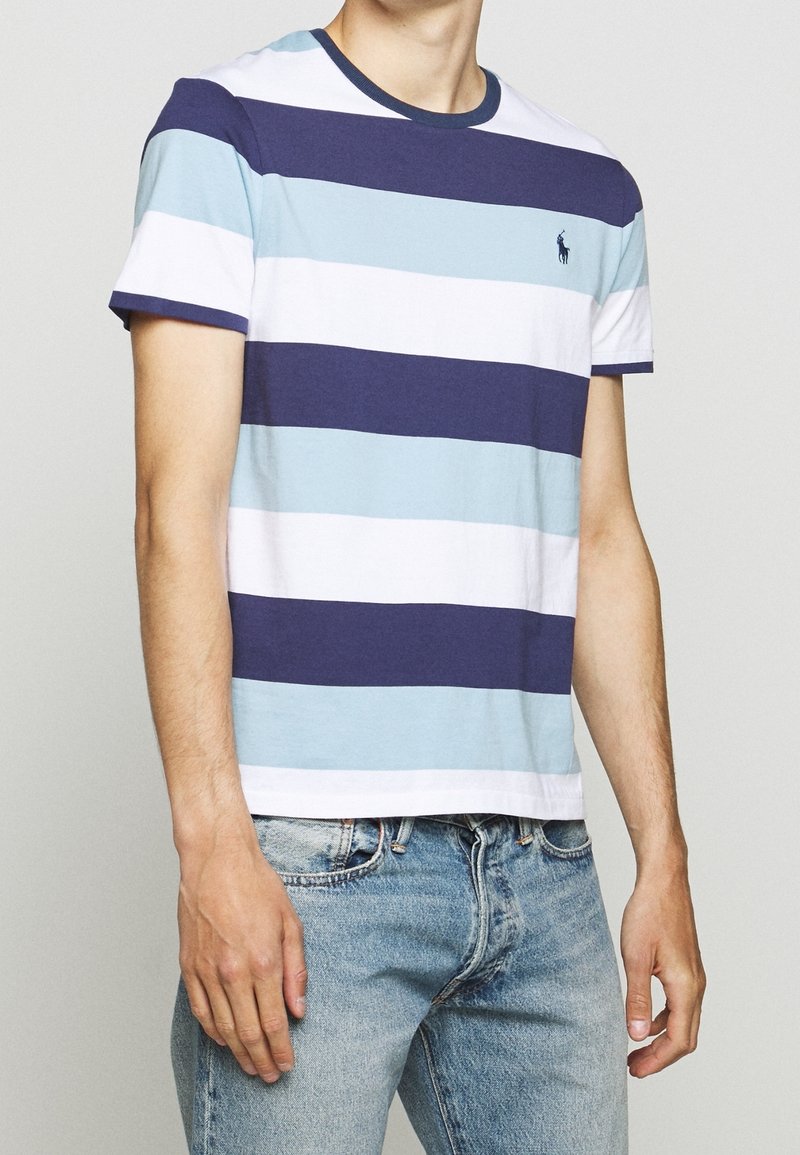 Maglietta a righe con righe orizzontali alternate in navy, azzurro chiaro e bianco. Collo a giroclassico con maniche corte, in materiale di cotone.