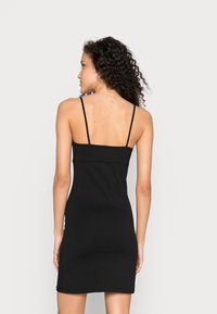 Vestido preto ajustado com alças finas, feito de um tecido elástico. Apresenta um design simples, sem padrões ou adornos.