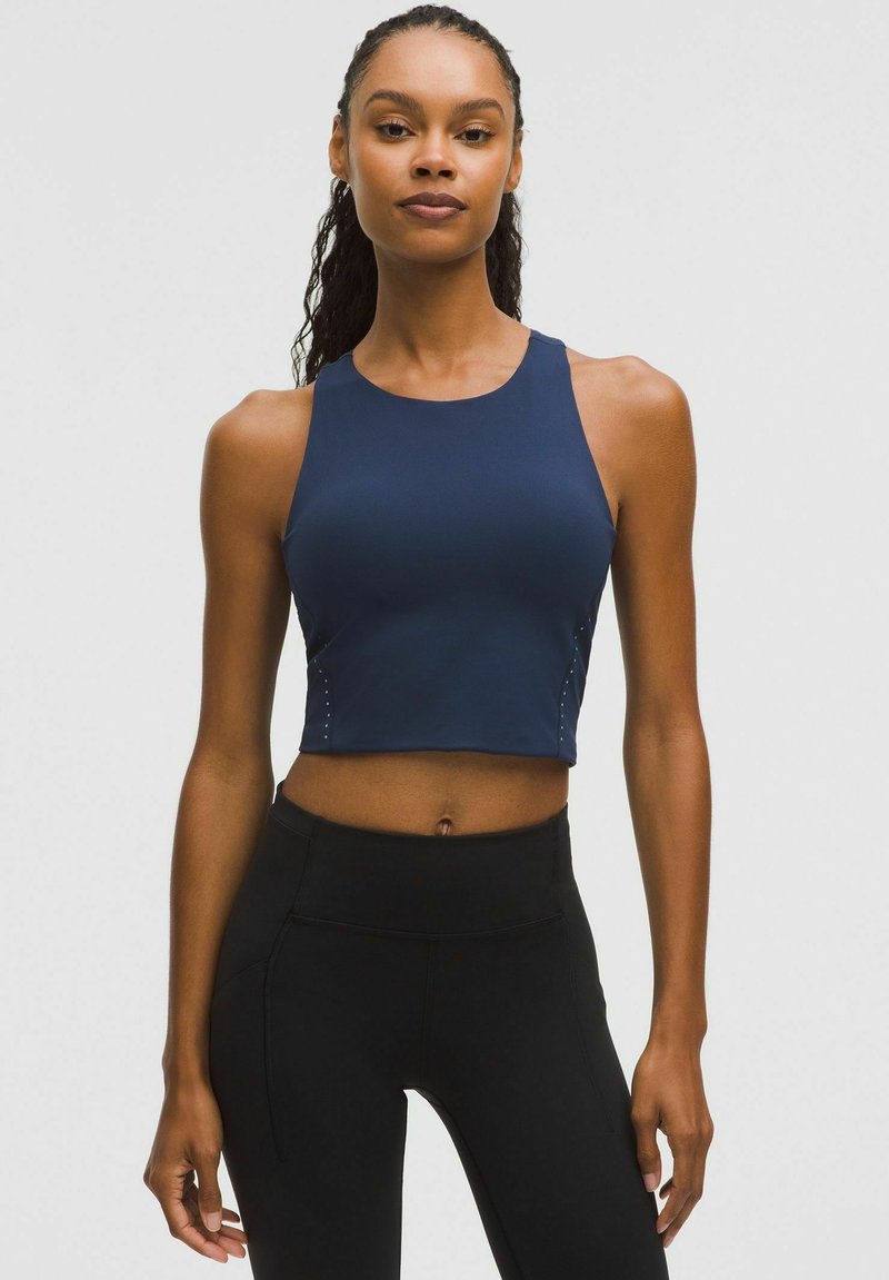 Navy cropped athletic top with a high neckline and side detailing. Styled with black high-waisted leggings, emphasizing a fitted design.