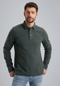 Donkergroene langemouwen polo met een gestructureerde stof, kraag en knoopsluiting. Logo-detail op de borst. Casual pasvorm ontwerp.