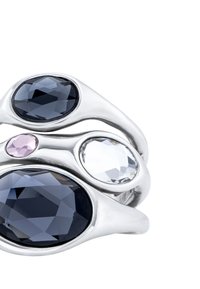 Anillo de metal tono plateado que presenta tres piedras facetadas: azul profundo, clara y rosa claro. Diseño curvado con textura suave y pulida.