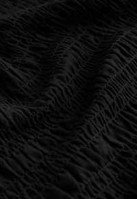 Tela negra con una textura arrugada, con pliegues verticales y un diseño elástico que crea un aspecto fruncido.