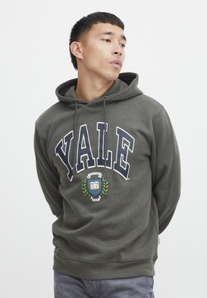 Oliven grøn hoodie af bomuld med "YALE" i hvide bogstaver og et rundt emblem med laurbærdesign. Justerbar snøring i hætten.