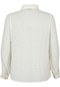 Bílá halenka s dlouhým rukávem zdobená šipkovým vzorem a volánkovým límečkem. Látka působí lehce, s rukávy na knoflíky a zaobleným lemem.