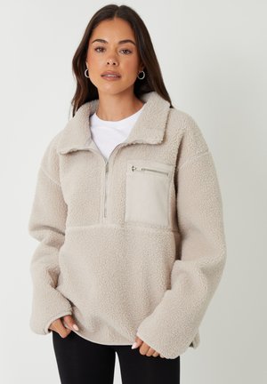 Licht beige fleece pullover met een ritssluiting bij de kraag en een voorkrupp pocket. Heeft een gestructureerde stof en losse mouwen.