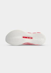 Semelle d'une chaussure de sport blanche et rouge avec une adhérence texturée, logo Adidas, gamme de tailles de 39,0 à 45,0, et marquage "LIGHTSTRIKE" visible.