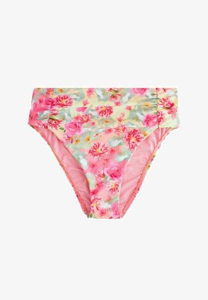 Prim-plan al unui material roz cu model floral cu flori roșii, albe și verzi purtat în talie, arătând o mică etichetă aurie de marcă.