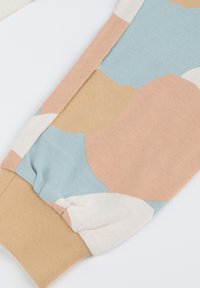 Soft cotton fabric, featuring abstract patterns in pastel colors of blue, peach, and beige. Elasticized cuffs and smooth texture.