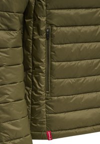 Olivenfarvet pufferjakke med vandret quiltet design, der har en lynlåslomme og en rød mærkelabel i den nederste side.