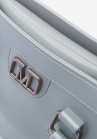 Lichtblauwe handtas van glad leer, met een metallic logo, decoratieve hardware en een gestructureerd ontwerp met een flapvergrendeling.