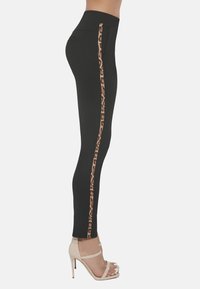 Czarne legginsy z wysokim stanem, z pionowym paskiem w leopardzi wzór po boku. Gładka tekstura, dopasowany krój.