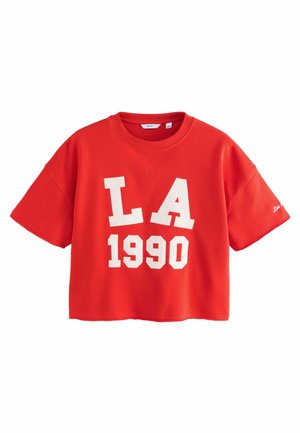 T-shirt rouge court en coton, arborant en grand les lettres blanches "LA" et "1990" imprimées sur le devant. Manches courtes.