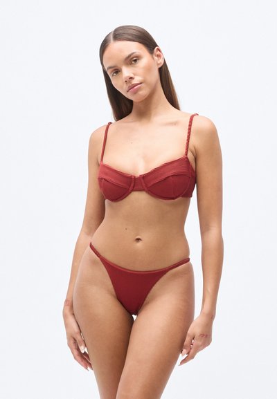 Κόκκινο ριμπ μαγιό σετ, με μπλούζα τύπου bralette με δομημένη εφαρμογή και ρυθμιζόμενους ιμάντες, καθώς και ταίριαστο ψηλόμεσο κάτω μέρος με λεπτά κορδόνια στο πλάι.