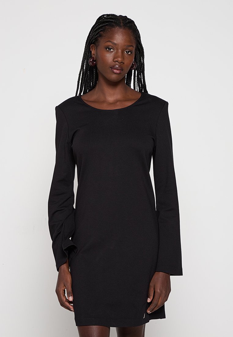 Czarna sukienka z długim rękawem w dopasowanym fasonie z okrągłym dekoltem. Wykonana z gładkiego materiału, posiada subtelne detale szwów i smukłą sylwetkę.