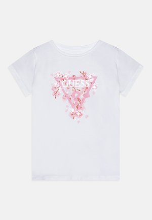 Biała bawełniana koszulka z różowym trójkątnym wzorem, na którym znajduje się napis "GUESS" oraz kwiatowe grafiki wokół. Krótkie rękawy i okrągły dekolt.