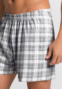 Grau-weiße karierten Boxershorts aus Baumwolle, mit einem elastischen Bund und einem lockeren Schnitt sowie einer glatten Textur.