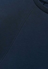 Mörkblå sweatshirttyg med en slät textur och en subtil glans. Har raglanärmar och förstärkt söm längs sömmarna.
