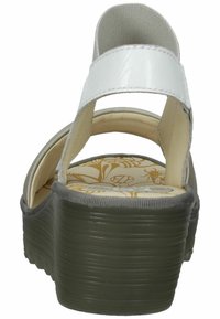 Weiße Riemchensandalen mit einer strukturierten grauen Plattform. Merkmale eine dekorative gepolsterte Innensohle mit floralem Muster. Die Rückansicht hebt die Höhe des Absatzes hervor.
