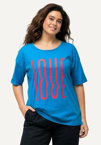 Camiseta azul con un atrevido gráfico en rojo de "LOVE". Mangas cortas con puños enrollados, fabricada en una tela suave y ligera.